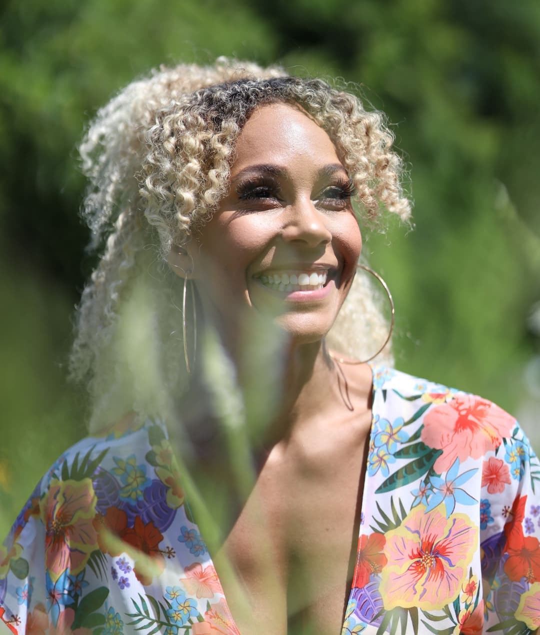 photo of a Black woman with blonde curly hair in a floral shirt.